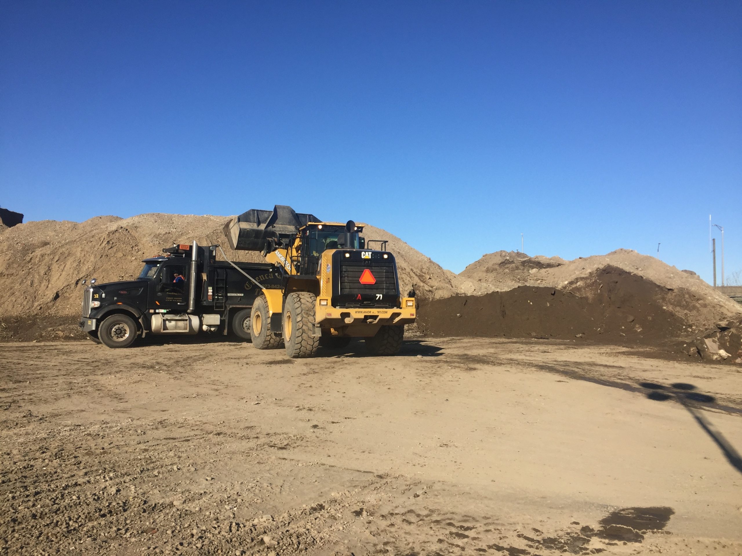 Excavator loading trucks with soil for disposal
